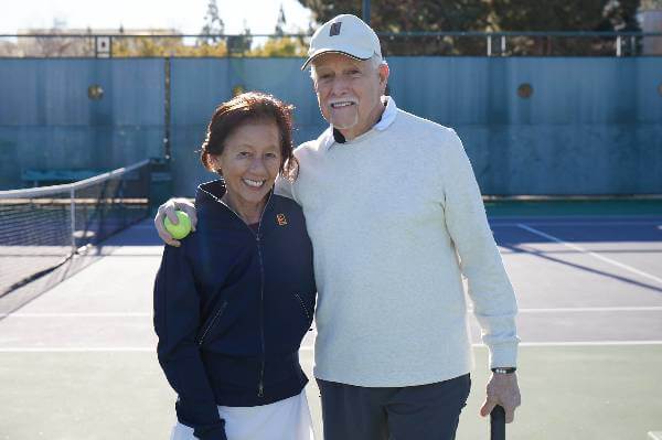 Two Medicare Advantage–enrolled seniors posing on a tennis court
