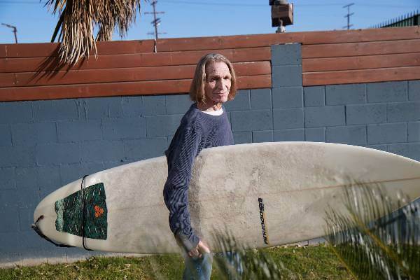 A Medicare Advantage–enrolled senior posing with a surf board