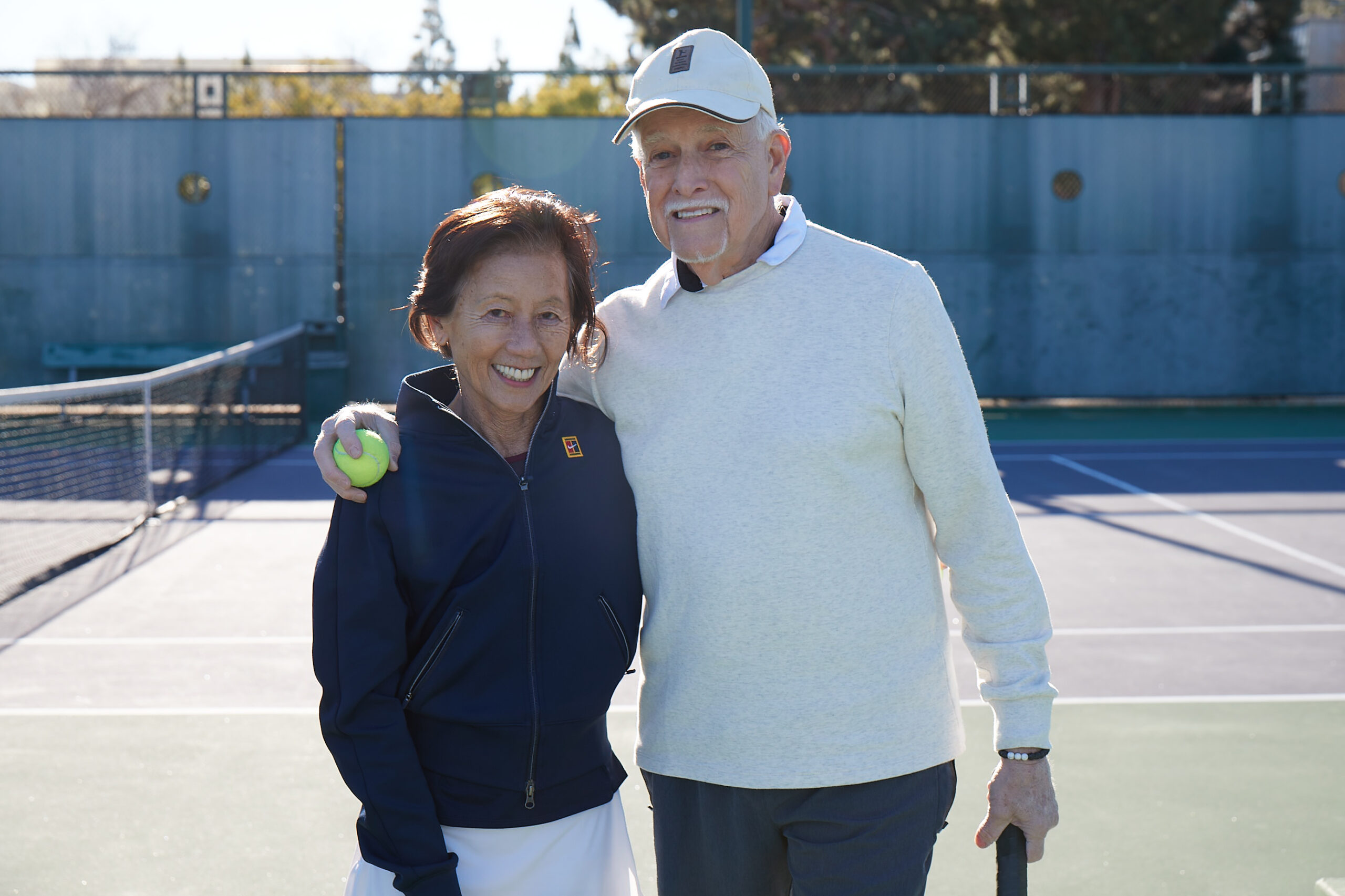 Two Medicare Advantage–enrolled seniors posing on a tennis court